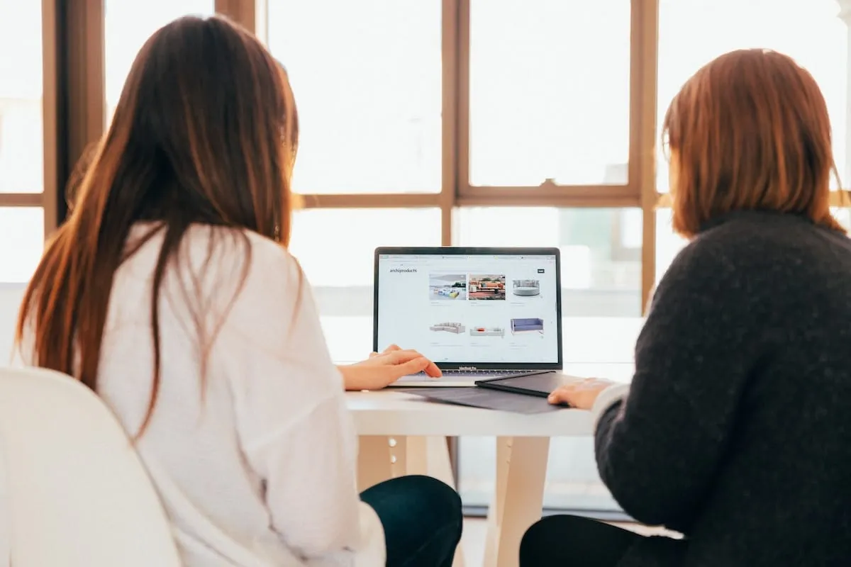 2 women sitting around a laptop discussing a PPC Advertising project
