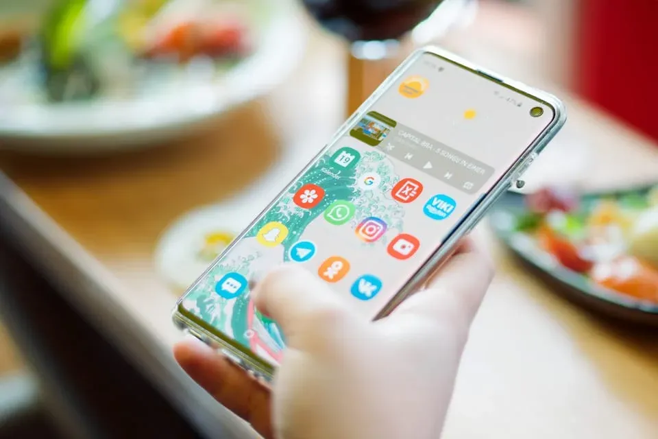 Phone in a hand showing social media icons on the home screen